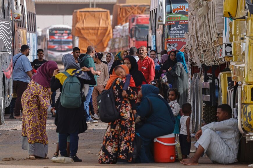 Passengers fleeing war-torn Sudan rest before crossing into Egypt through the Argeen border