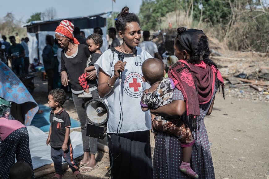 A Red Cross volunteer helps refugees from Sudan who crossed into Ethiopia at Metema