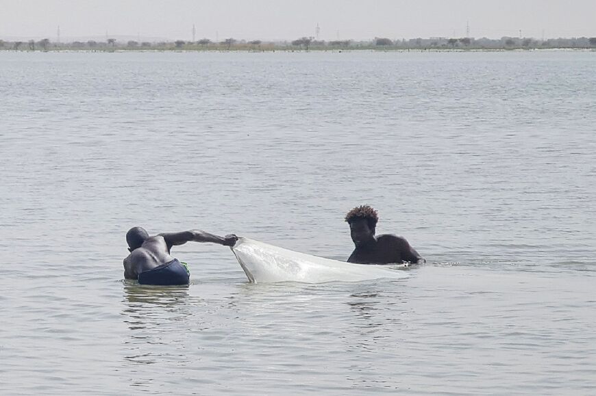 Youths pull a fishing net from the White Nile river in Khartoum, during the relative calm following a ceasefire