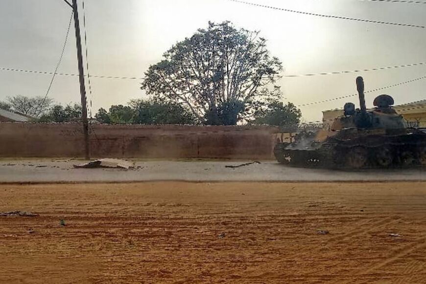 A covered body lies across from a miliatry armoured vehicle on a street in the West Darfur state capital El Geneina