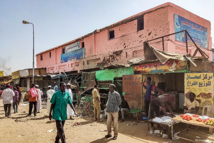 People walk past a medical centre riddled with bullet holes in the Sudanese capital's Souk Sitta