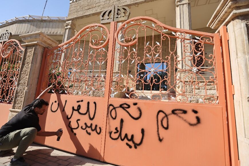 A man sprays graffiti reading 'Yes, yes to the Koran' at the entrance to the Swedish embassy in Baghdad