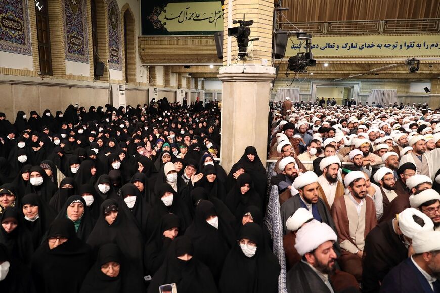 Women and men listen to Iran's Supreme Leader Ayatollah Ali Khamenei speak