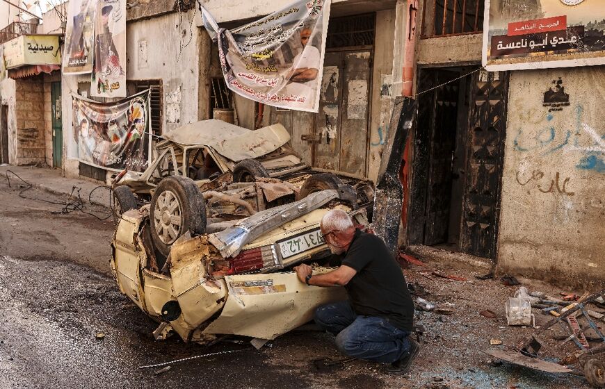 A man checks a wrecked car in the aftermath of the military operation in Jenin refugee camp in the occupied West Bank on July 5, 2023