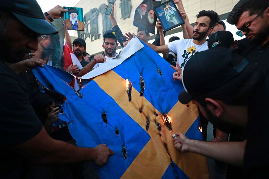 Iraqi protesters burn a Swedish flag during a protest in Baghdad's Tahrir square