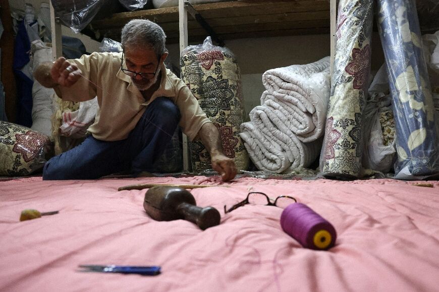 Mustafa al-Qadi, 67, often mends duvets under the soft light of a window during one of Lebanon's long power cuts