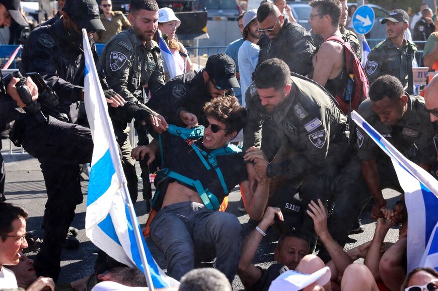 Israeli security forces remove demonstrators blocking the entrance to parliament ahead of a final vote on a major component of the government's proposed judicial revamp