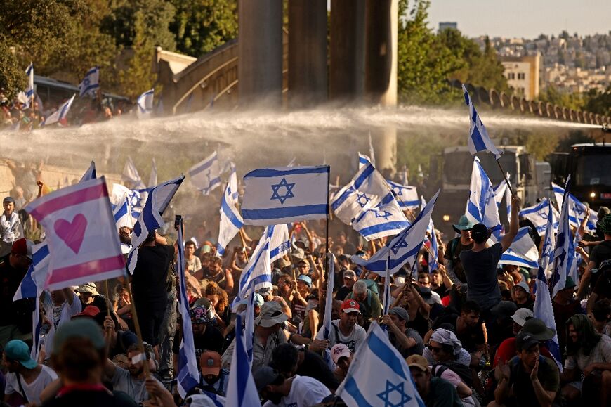 Israeli security forces use a water cannon to disperse demonstrators blocking the entrance of Israel's parliament in Jerusalem