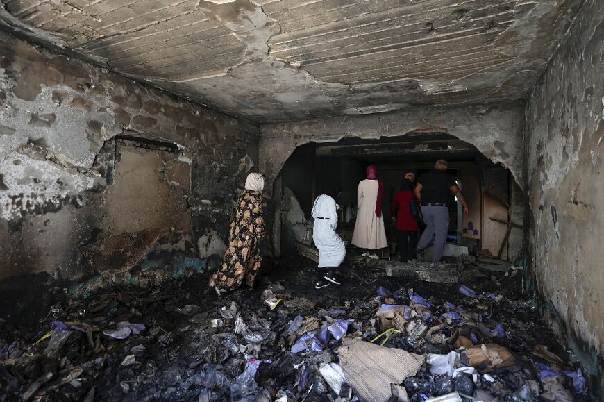 Residents assess the damage inside a shop in Jenin refugee camp after a major Israeli military operation