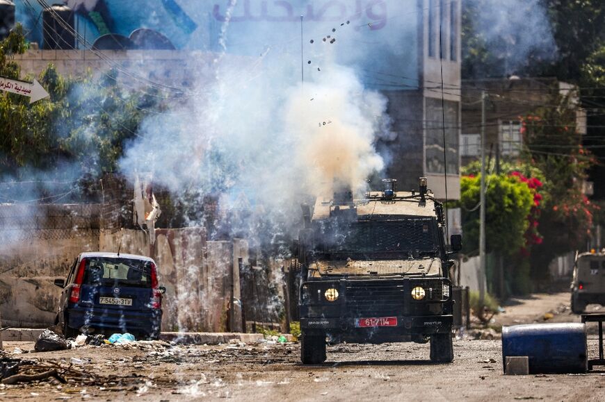 Israeli soldiers fire tear gas canisters from an armoured vehicle during the military operation