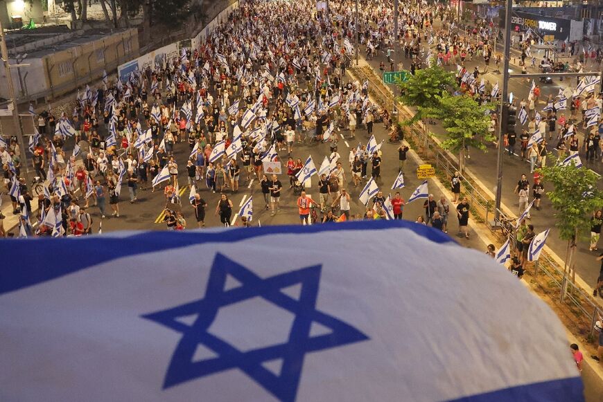 Protesters lift flags as they march against the Israeli government's judicial overhaul plan in Tel Aviv on July 29, 2023