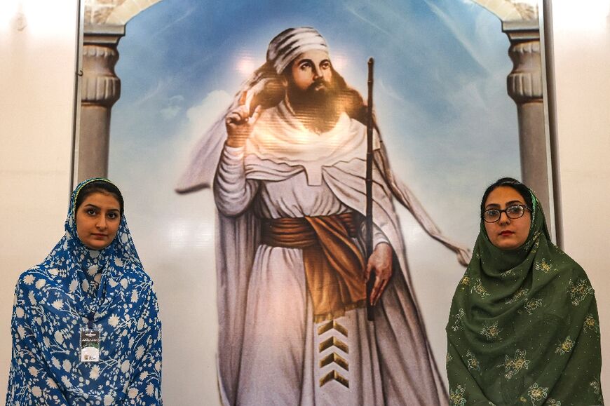 Farnaz (L) and Simin, tour guides at the Fire Temple of Yazd, stand before an image depicting  Zarathustra, spiritual founder and prophet of Zoroastrianism. Today, the Zoroastrian community is estimated to number 200,000,  mainly in Iran and India.