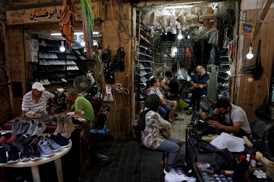 Workers repair shoes as customers wait in Ahmed al-Bizri's store in Lebanon's coastal city of Sidon