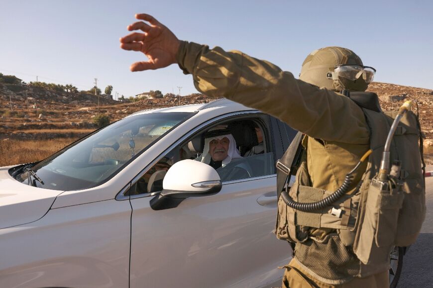 Israeli troops block a road south of Hebron as they press a manhunt for those behind the deadly Monday shooting of an Israeli settler near the West Bank city