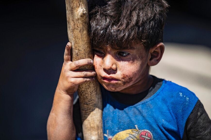 A boy stands near his tent at the Sahlat al-Banat makeshift camp for displaced people set up next to a waste dump on the outskirts of the northern Syrian city of Raqa