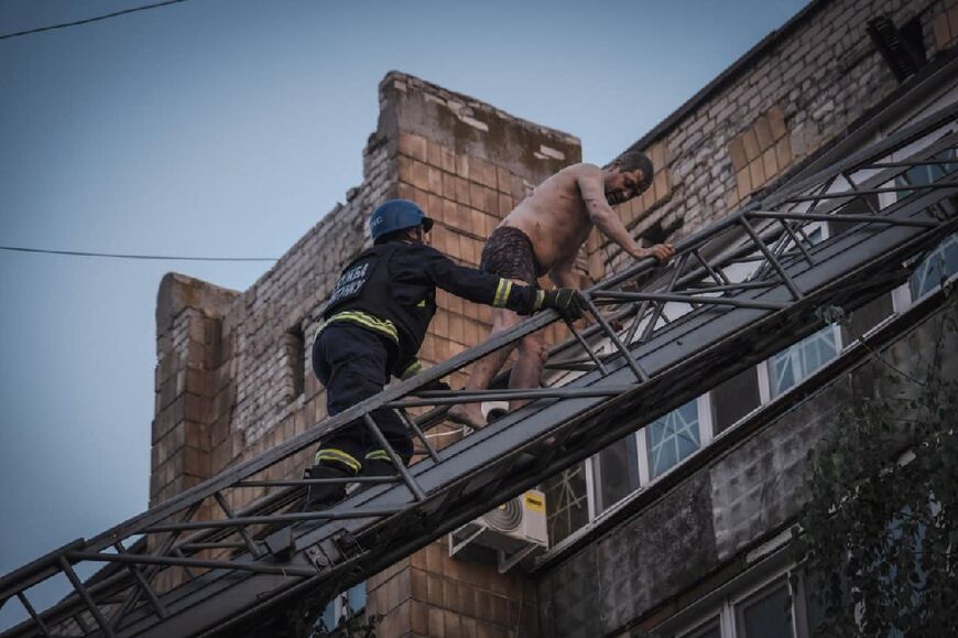 A rescuer evacuates a resident from a damaged building after Russian missiles strikes in Pokrovsk