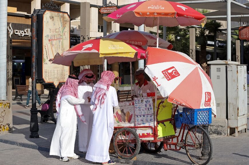 Multiple umbrellas shade an ice cream stand against the scorching desert sun