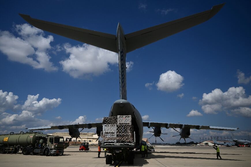 French servicemen and emergency personnel load cargo onto a an Air Force Airbus to send assistance to Libya 