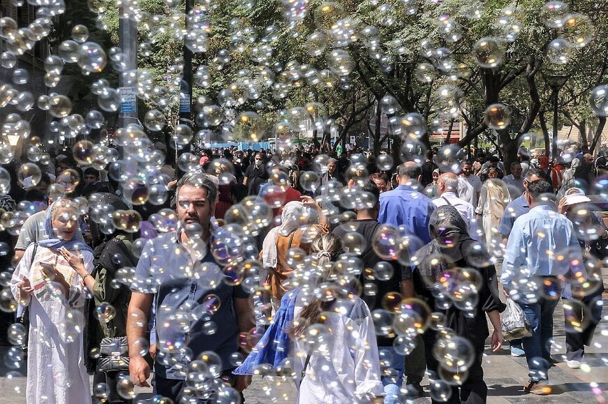 Bubbles blown by a merchant surround people walking outside the Grand Bazaar in Tehran