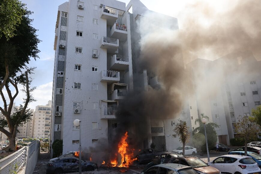 Cars burn beneath a residential building during a rocket attack from Gaza on the Israeli city of Ashkelon