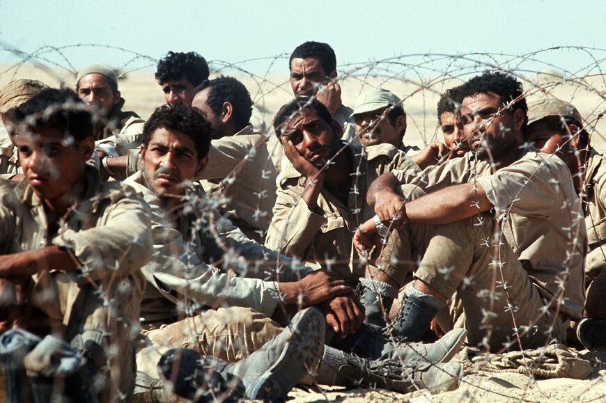 Egyptian troops captured by Israel sit at a camp near the Suez Canal during the 1973 war