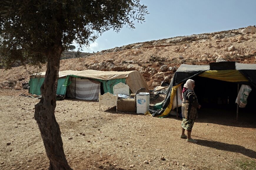 A woman from Wadi al-Seeq walks toward temporary shelters set up in the nearby town of Taybeh where the villagers have taken refuge after being thrown off their own lands