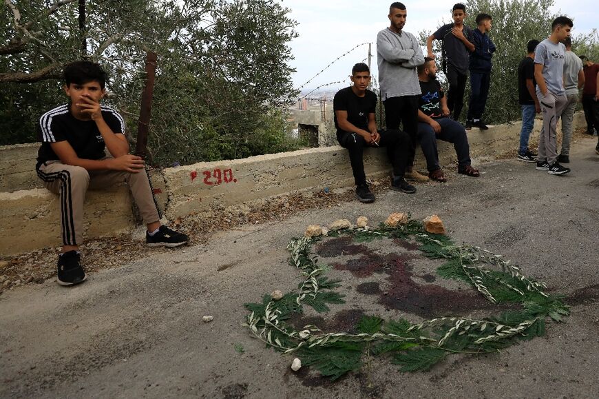 People gather around a blood stain surrounded with leaves near the West Bank city of Tulkarm where two Palestinians were reportedly killed during clashes with Israeli forces
