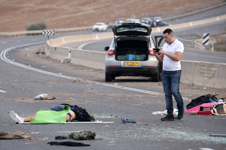 A man takes a picture of a body on a road close to the border with Gaza 