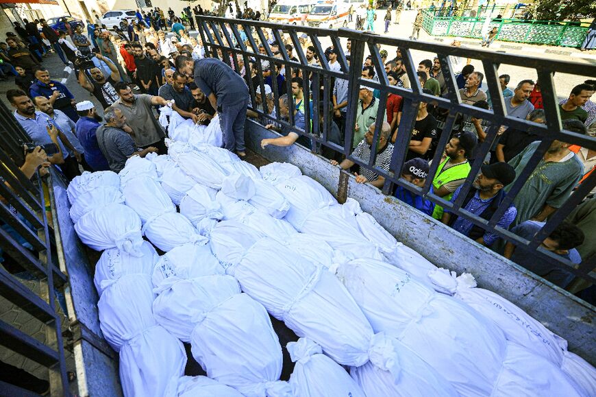 A lorry carries bodies of Palestinians killed in a shelter for internally displaced people, as they are taken for burial from the Al-Aqsa hospital in the town of Deir Al-Balah, in the central Gaza Strip, on October 15, 2023