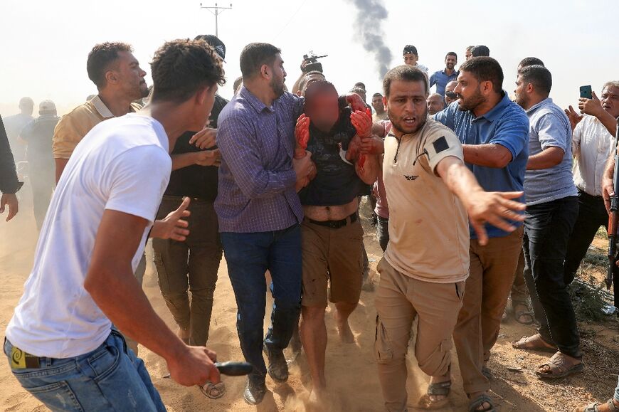 Palestinians curround a reportedly captured and injured Israeli man, in Khan Yunis in the southern Gaza Strip, on October 7, 2023