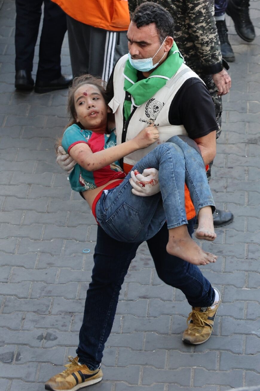 A man carries a wounded child into al-Shifa hospital following Israeli strikes in Gaza City 