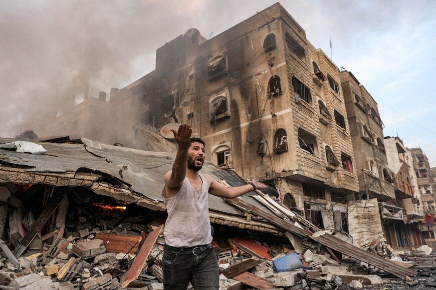 A man outside a burning collapsed building following Israeli bombardment in Gaza City on October 11, 2023
