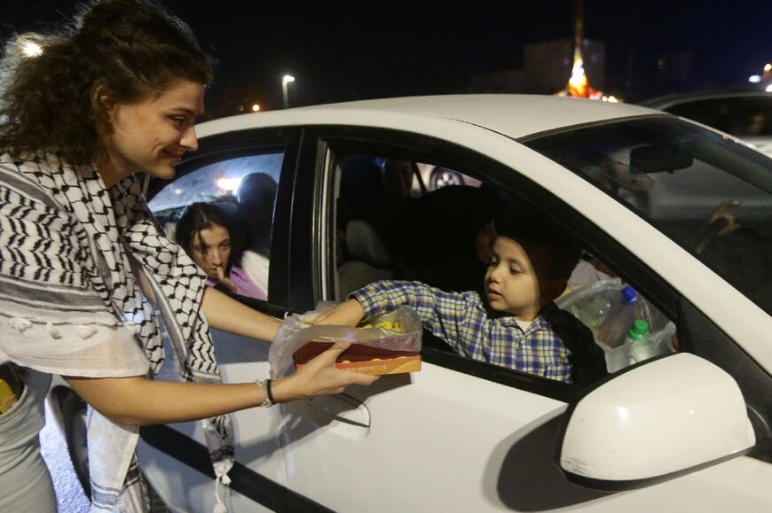 A woman passes out sweets to passers by in Damascus on October in a show of solidarity with the Palestinian people following the multi-pronged assault by Hamas on Israel