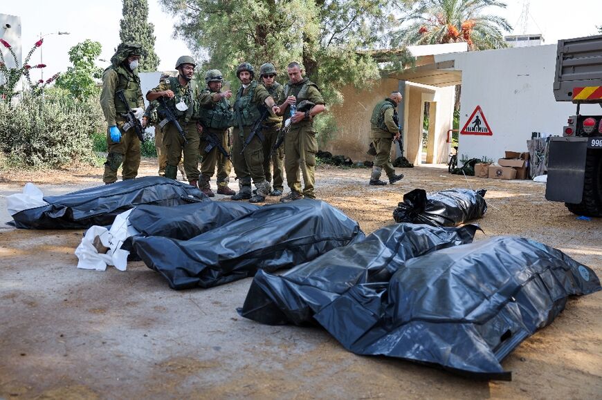 Israeli soldiers prepare to remove the bodies of compatriots killed by Palestinian militants in the kibbutz of Kfar Aza where more than 100 civilians are believed to have been massacred