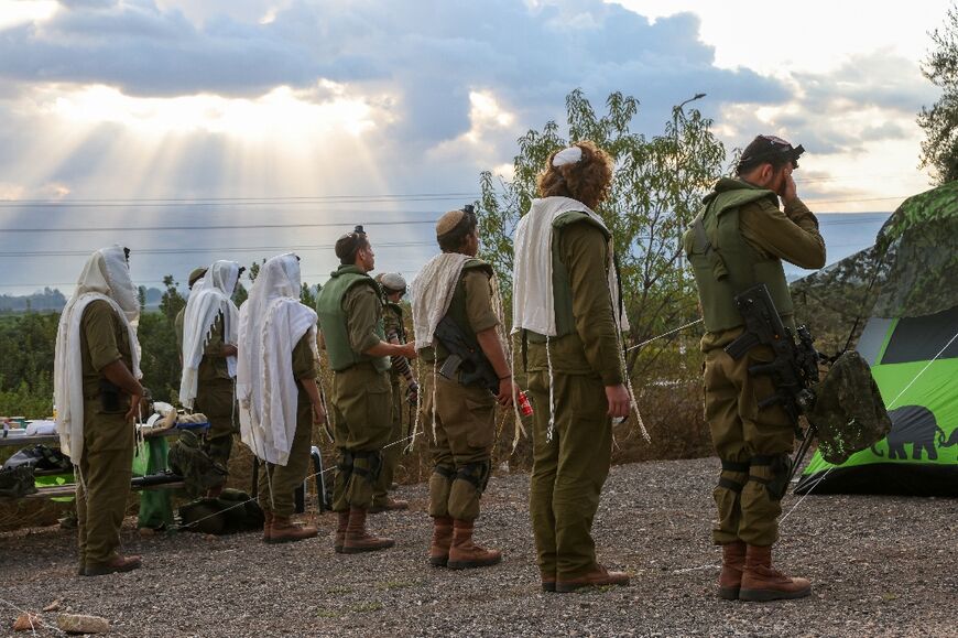 Israeli soldiers pray at their position in the north of Israel near the border with Lebanon on October 15, 2023