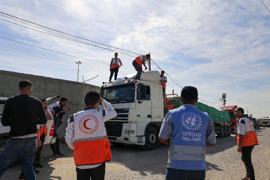 Aid workers gather around trucks carrying humanitarian aid that entered the Gaza Strip from Egypt via the Rafah border crossing on October 21, 2023