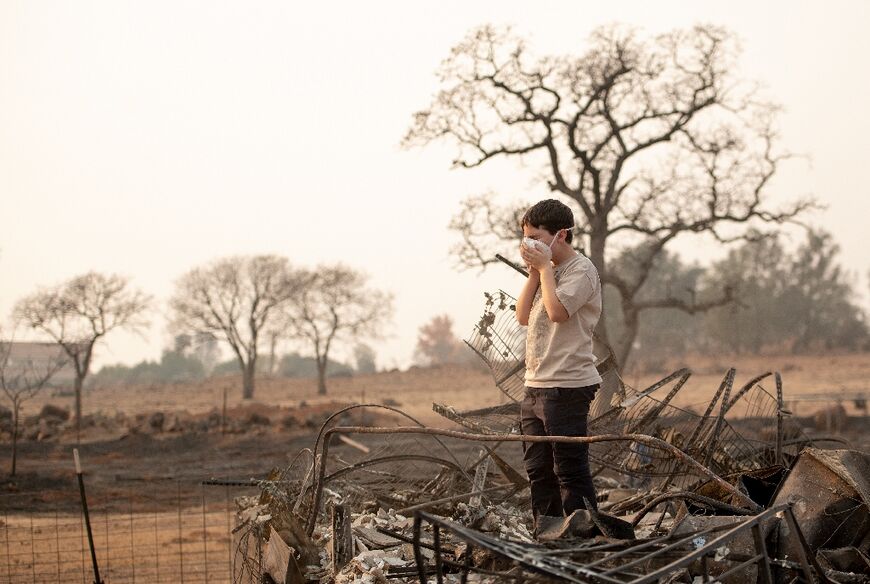 Jeremie Saylors, 11, adjusts his face mask while searching through the burned remains of his home in Paradise, California on November 18, 2018; his family lost a home in the same spot to a fire 10 years prior