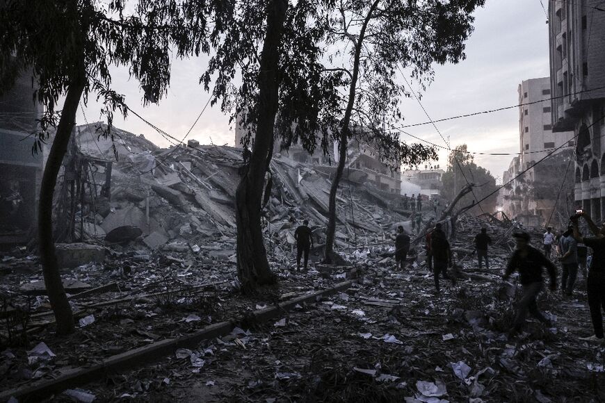 People walk atop the rubble of a tower destroyed in an Israeli air stike in Gaza City 