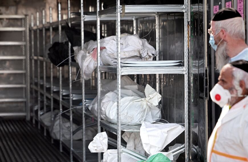 Israeli forensic members and soldiers gather next a container where the bodies of Israeli casualties are being stored at the army base in Ramla, on October 13, 2023, amid the ongoing battles between Israel and the Palestinian Islamist group Hamas
