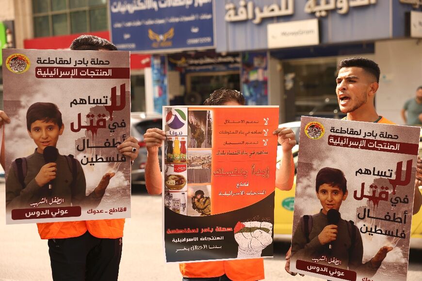 Palestinians hold posters demanding a boycott of Israeli products during a rally in the occupied West Bank city of Hebron