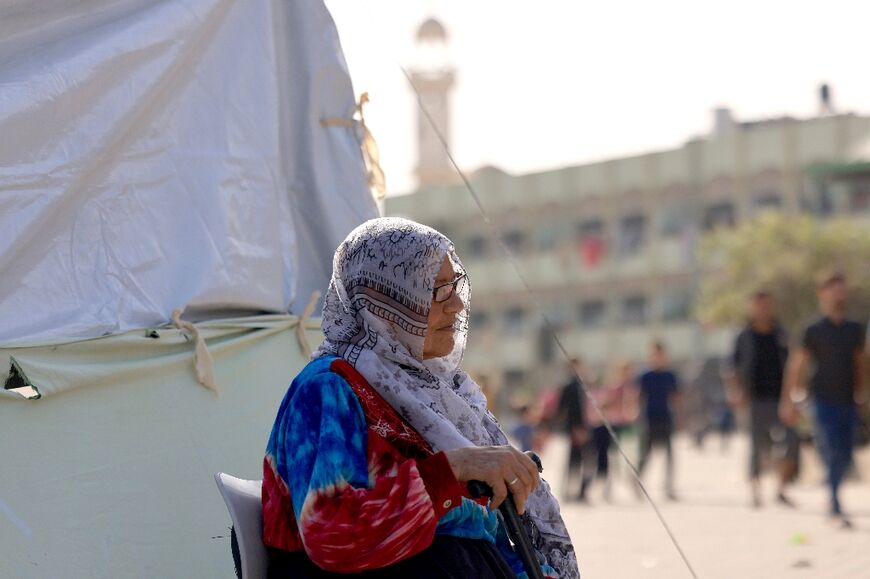 A displaced woman sits outside a makeshift tent in the grounds of a school in Khan Yunis