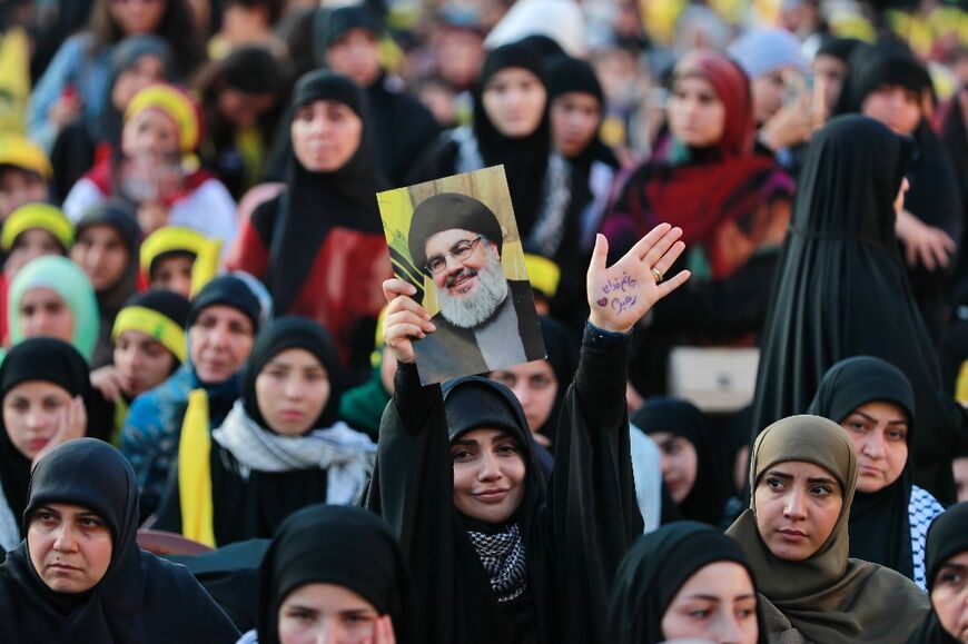 A Hezbollah supporter holds up a portrait of Nasrallah at the live screening of his speech in Beirut's southern suburbs