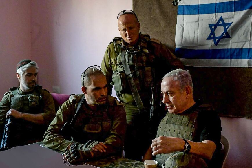 In this handout picture taken and released by the Israeli Prime Minister's Office on November 26, 2023 Israeli Prime Minister Benjamin Netanyahu (R) meets soldiers at an undisclosed location in the Gaza Strip