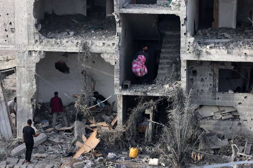 People salvage some belongings from a damaged building following bombing in the southern Gaza Strip