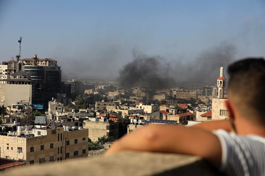 A child watches smoke rising from the Jenin Palestinian refugee camp, during clashes after an Israeli raid