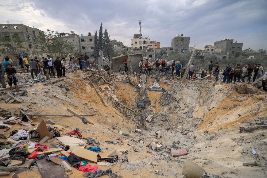 People stand over a crater following Israeli bombardment in the southern Gaza Strip 