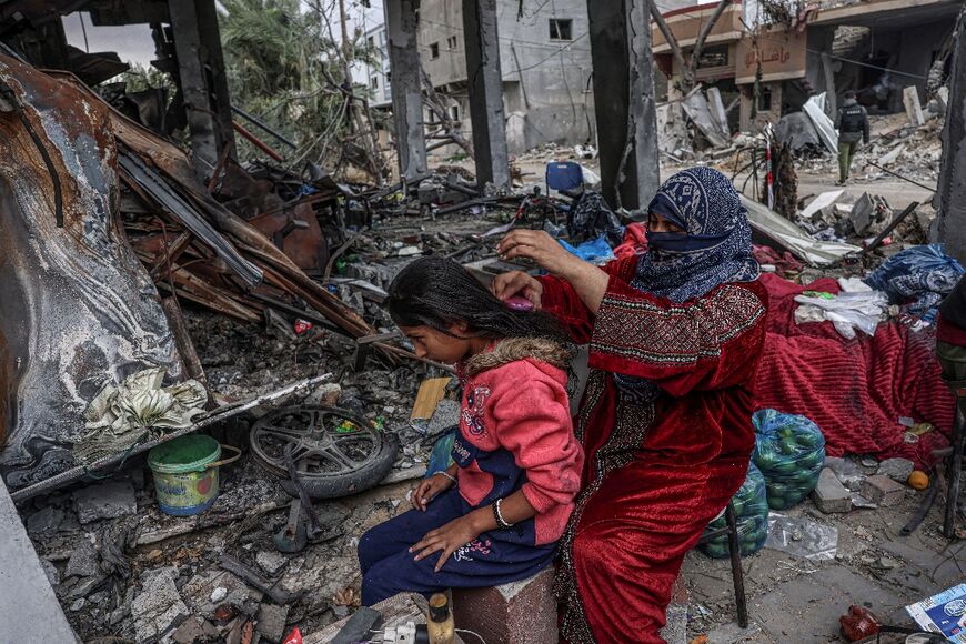 A Palestinian woman brushes a girl's hair in the war-torn Gaza Strip, where many homes have been reduced to rubble