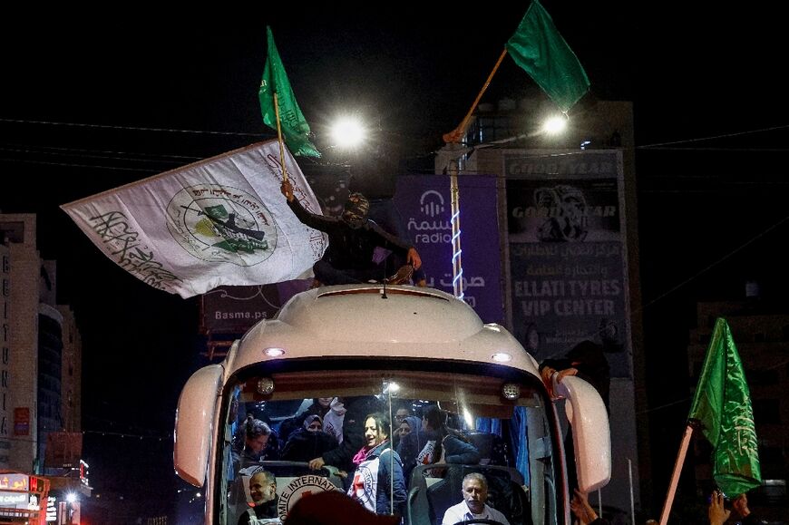 Men wave the Hamas flag as a crowd in the occupied West Bank surrounds a Red Cross bus carrying Palestinians released from Israeli prisons