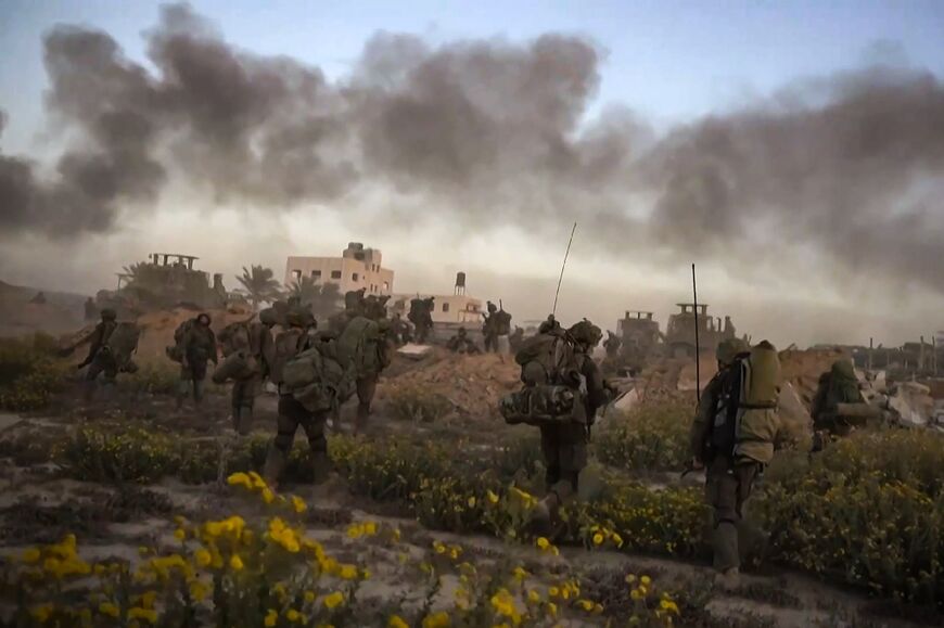 This image grab from a handout video released by the Israeli army on November 11, 2023, shows smoke rising as Israeli forces patrol inside the Gaza Strip