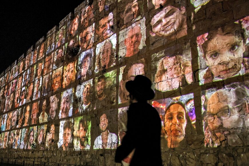 An ultra-Orthodox Jewish man walks outside the walls of the old city of Jerusalem, on which are projected pictures of the hostages abducted by Palestinian militants on the October 7 attack 